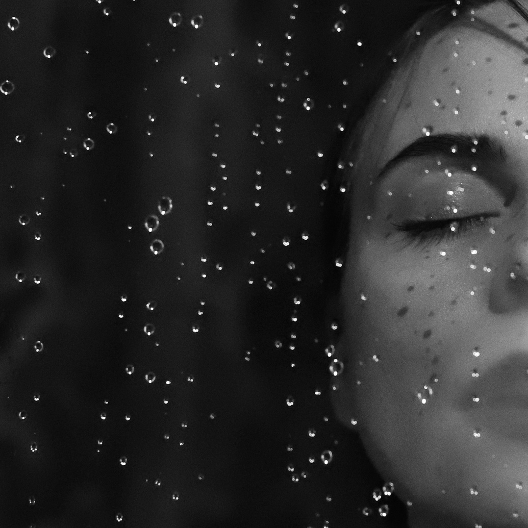 Black and White Portrait of Beautiful Woman Behind Wet Glass
